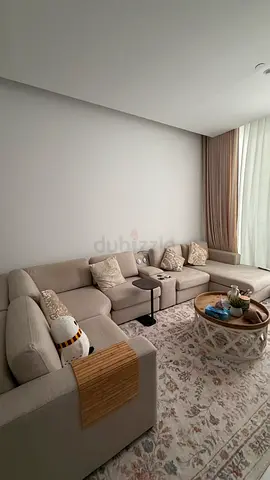 Light beige L-shaped sectional sofa with coffee table and rug