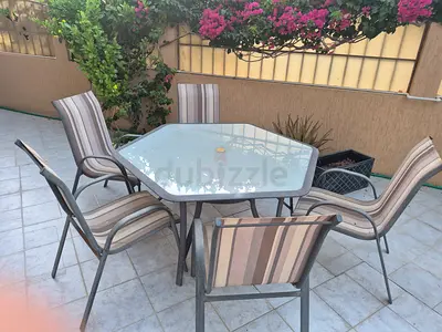 Outdoor glass-top patio table with 5 striped chairs - good condition