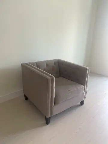 Single grey upholstered armchair with button-tufted back
