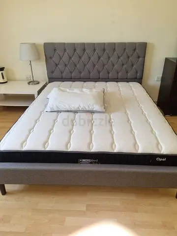 Queen-sized grey upholstered bed frame with mattress (good condition)