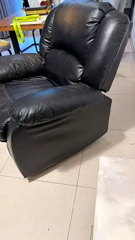 Used black leather reclining armchair — worn armrest, functional