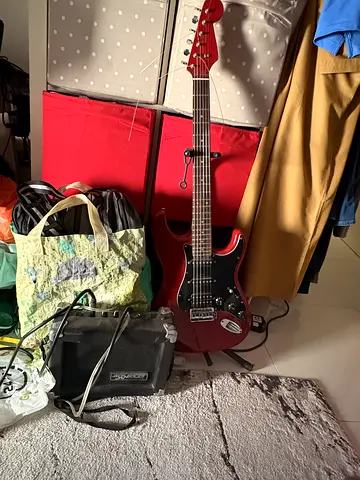 Red electric guitar with small practice amp -used, E string and A string don’t seem to tune properly