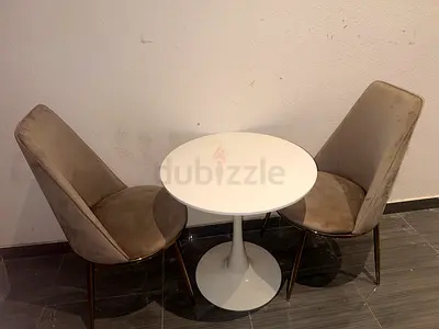 Small White Tulip Table With Two Grey Velvet Accent Chairs with Gold Legs.