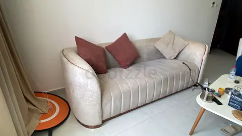 Light beige 3-seater sofa with wooden base and cushions - good condition. Original price 1900 AED