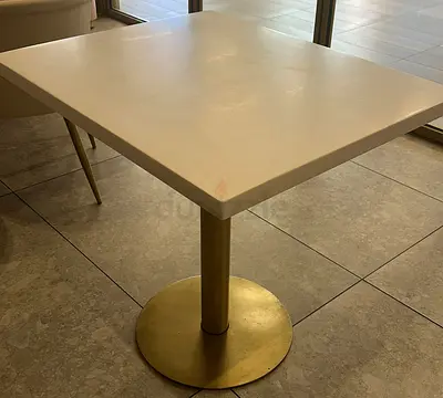Square white café table with brass pedestal base