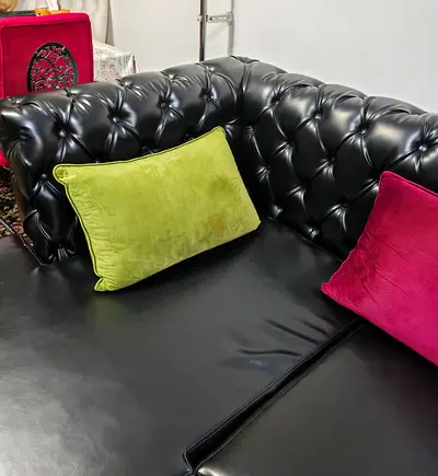 Black Faux Leather Chesterfield-style 7-seater Sofa with multi colored cushions and center table.
