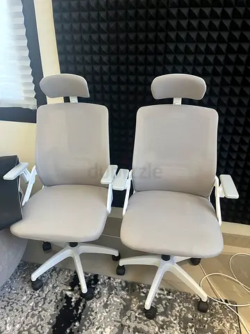 Pair of ergonomic grey office chairs with headrests
