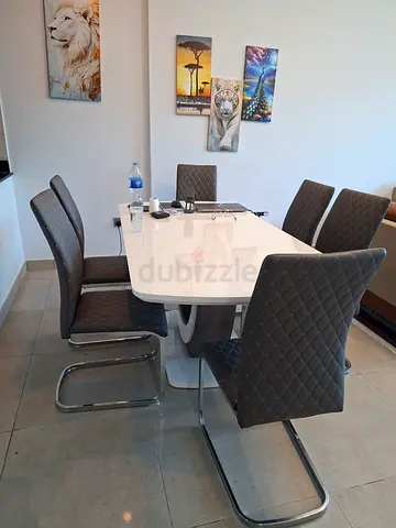 Modern white dining table with 6 grey quilted cantilever chairs