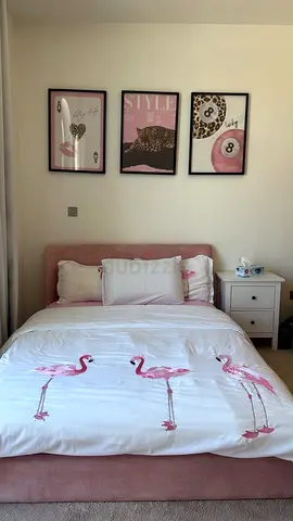 Single pink upholstered bed with flamingo duvet and bedside table
