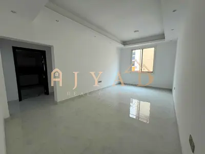 2BR hall first occupancy, Al Mowaihat 3 Ajman, prime location near schools/services, easy Dubai exit, 2 master rooms, 3 baths, central AC.