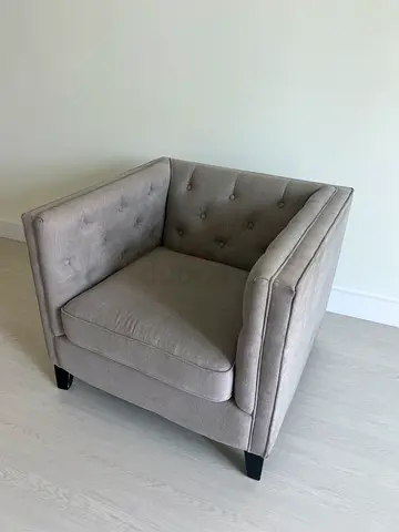 Single grey upholstered armchair with button-tufted back