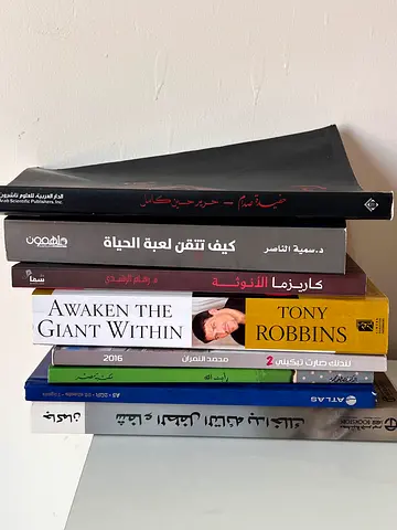 Collection of mixed personal development and Arabic books including Awaken the Giant Within