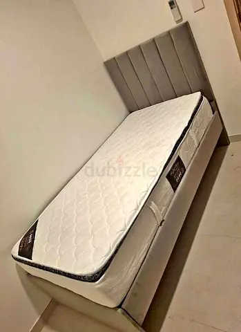 Single bed with grey upholstered headboard and mattress