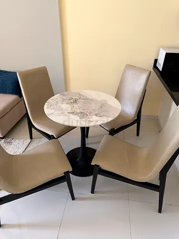 Compact round marble-top dining table with 4 beige chairs. Price is 450 aed. WhatsApp to discuss.
