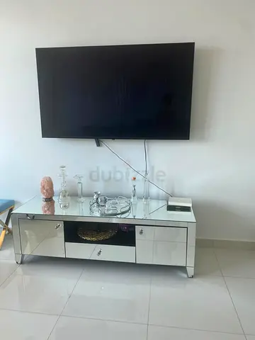 Modern glass TV unit with storage drawers. Clean and elegant design, suitable for living room or bed