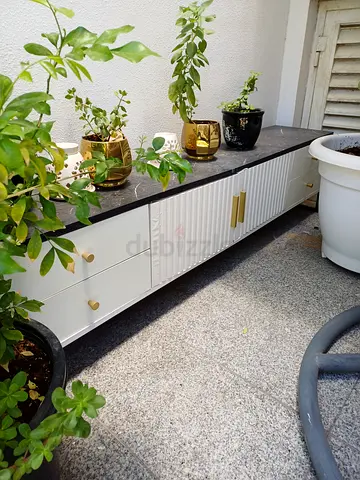 Low white TV cabinet/console with black top and gold handles
