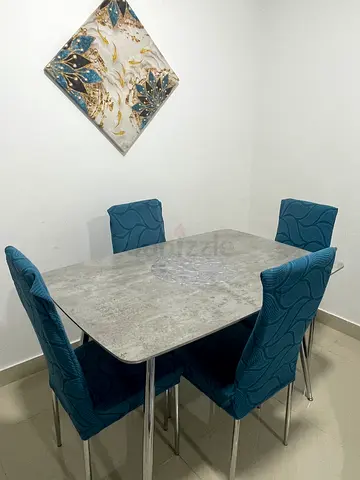 Modern concrete-look dining table with 4 teal upholstered chairs