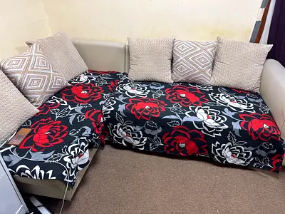 L-shaped beige faux leather sofa with floral covers and six cushions 50*50cm