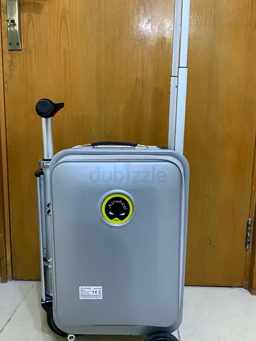 Small silver hard-shell carry-on suitcase with telescopic handle scooter