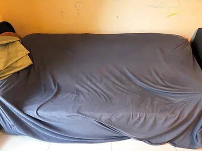 Used 3-seater sofa covered with grey slipcover