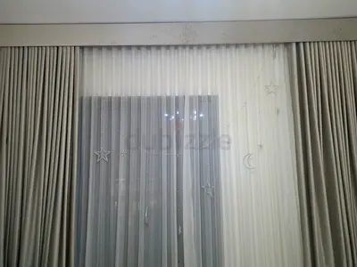 Pair of beige blackout curtains with white sheer voile