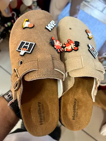 Light brown suede slip-on clogs with decorative pins, size unknown