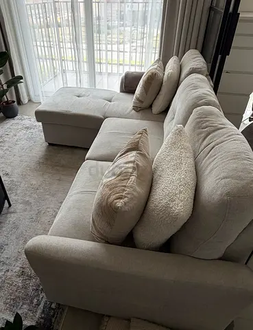 Light grey L-shaped fabric sofa with chaise, bed and storage