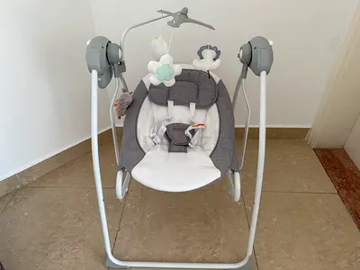 Gray electric baby swing BumbleBird with toys — gently used + baby bouncer from Baby Bjorn