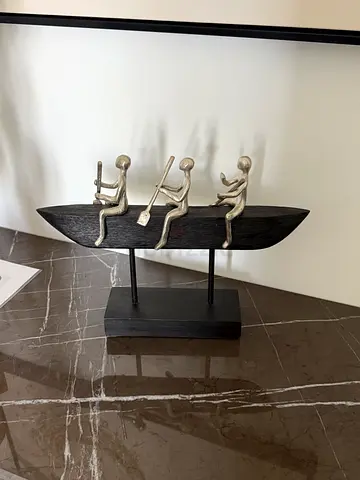 Decorative metal sculpture of three figures in a canoe