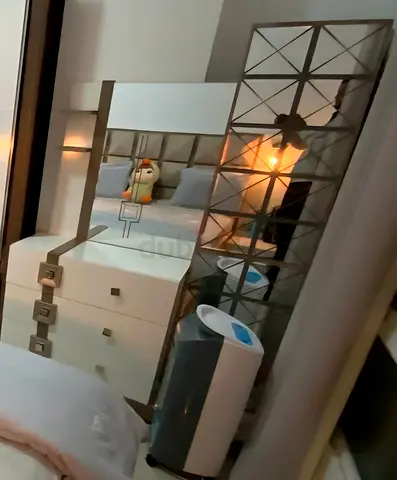 White bedroom dresser with mirror and decorative side panel with lights.