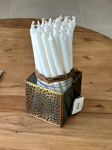 Bundle of white dinner candles with decorative metal holder