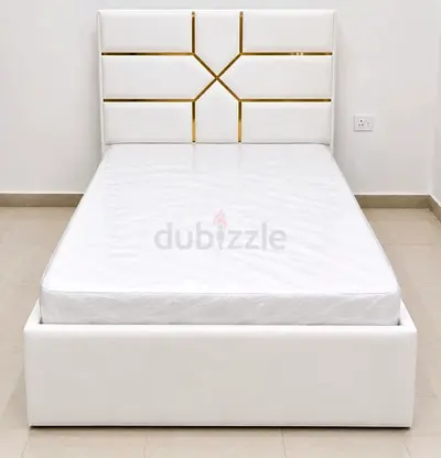 White upholstered single bed with mattress and gold-accented headboard