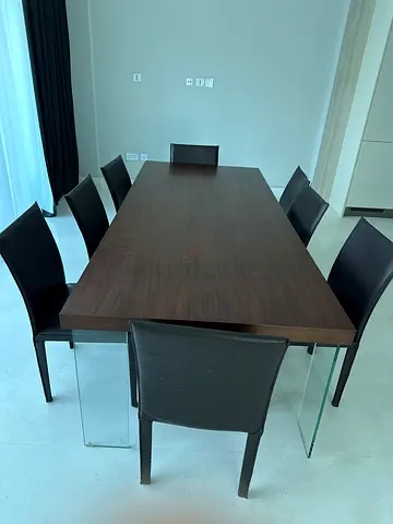Modern dark wood dining table with 8 black leather chairs