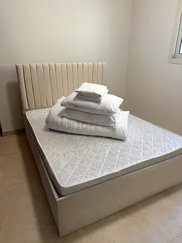Queen upholstered bed frame with mattress and bedding
