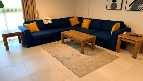 Large L-shaped navy sofa with wooden coffee and side tables