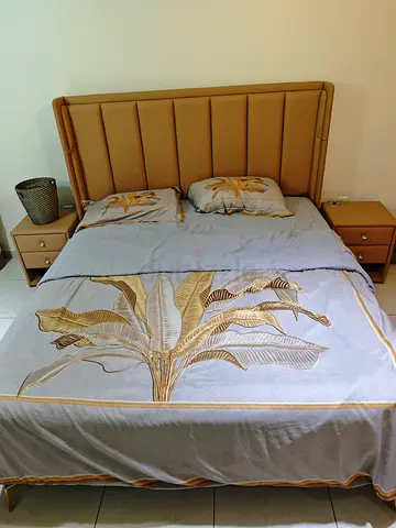 Beige upholstered queen bed with matching bedside tables and metress