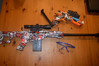 Two toy rifles (one bolt-action style and one dart blaster) with scope and safety glasses