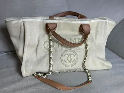Cream canvas tote with pearl-embellished logo and chain straps