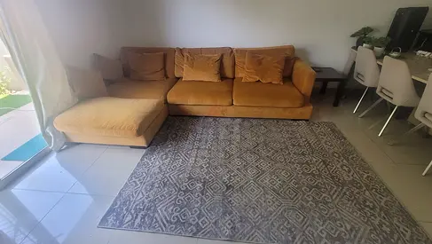 L-shaped mustard sofa with grey patterned rug excellent condition . From the luxurd  THE ONE