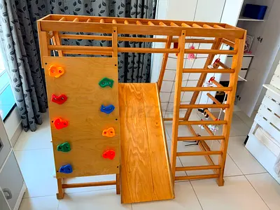 Wooden indoor or outdoor climbing gym with slide, swing and climbing wall