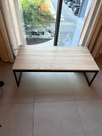 Minimalist rectangular coffee table with wood top and black metal legs.