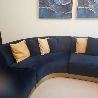Curved navy blue velvet sectional sofa with gold trim
