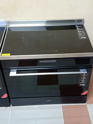 Omega 90cm induction cooker (model OFOIC909B) featuring a black glass cooktop and a digital display.