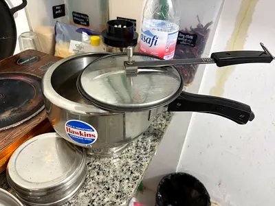 Small stainless steel pressure cooker with lid and handle - used