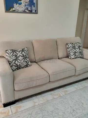 SUPER COMFY beige 3-Seater Fabric Sofa with Nailhead Trim and 2 grey floral accessory cushions