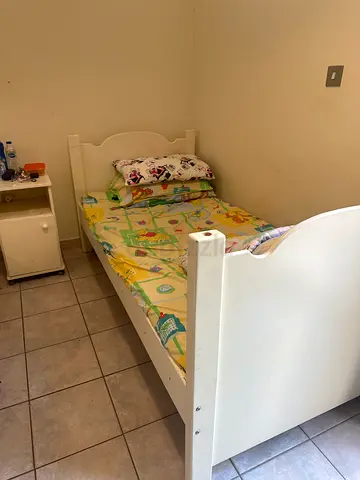 White toddler bed with mattress and small bedside cabinet