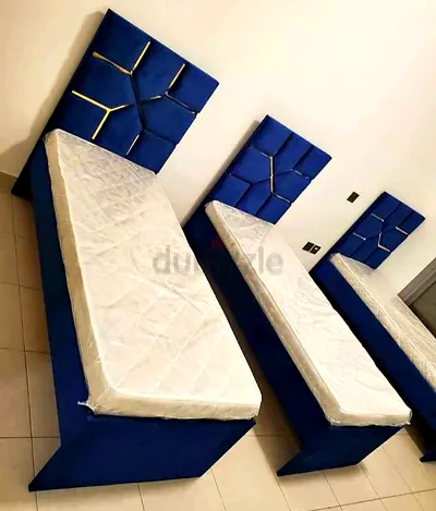 Three single beds with blue upholstered headboards and mattresses - good condition