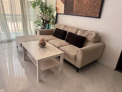 Light beige L-shaped sofa with chaise and matching white coffee table