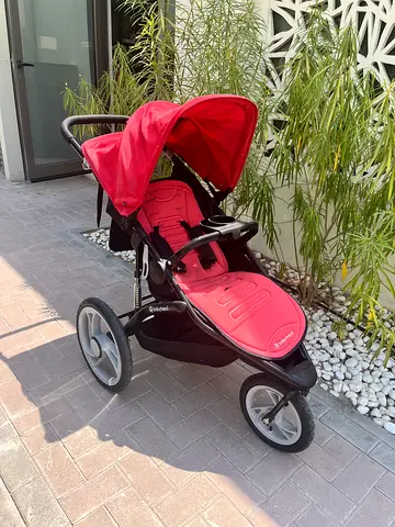 Red three-wheel jogging stroller in good condition
