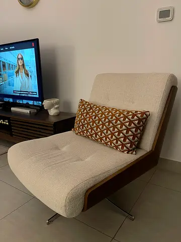 Modern single-seater lounge chair with wooden frame and cream upholstery